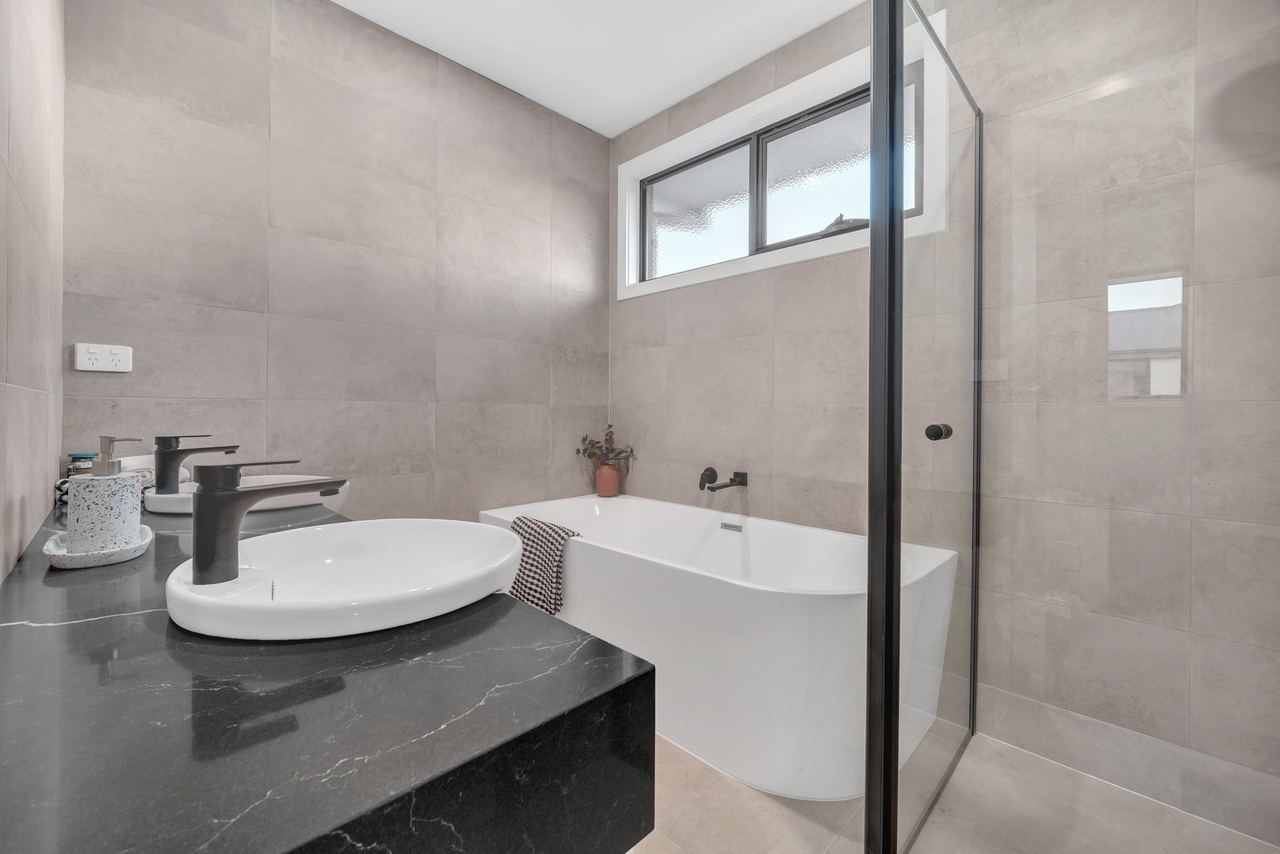 Bathroom in a new Berwick home with a freestanding bath, round basin on a dark stone top and frameless shower