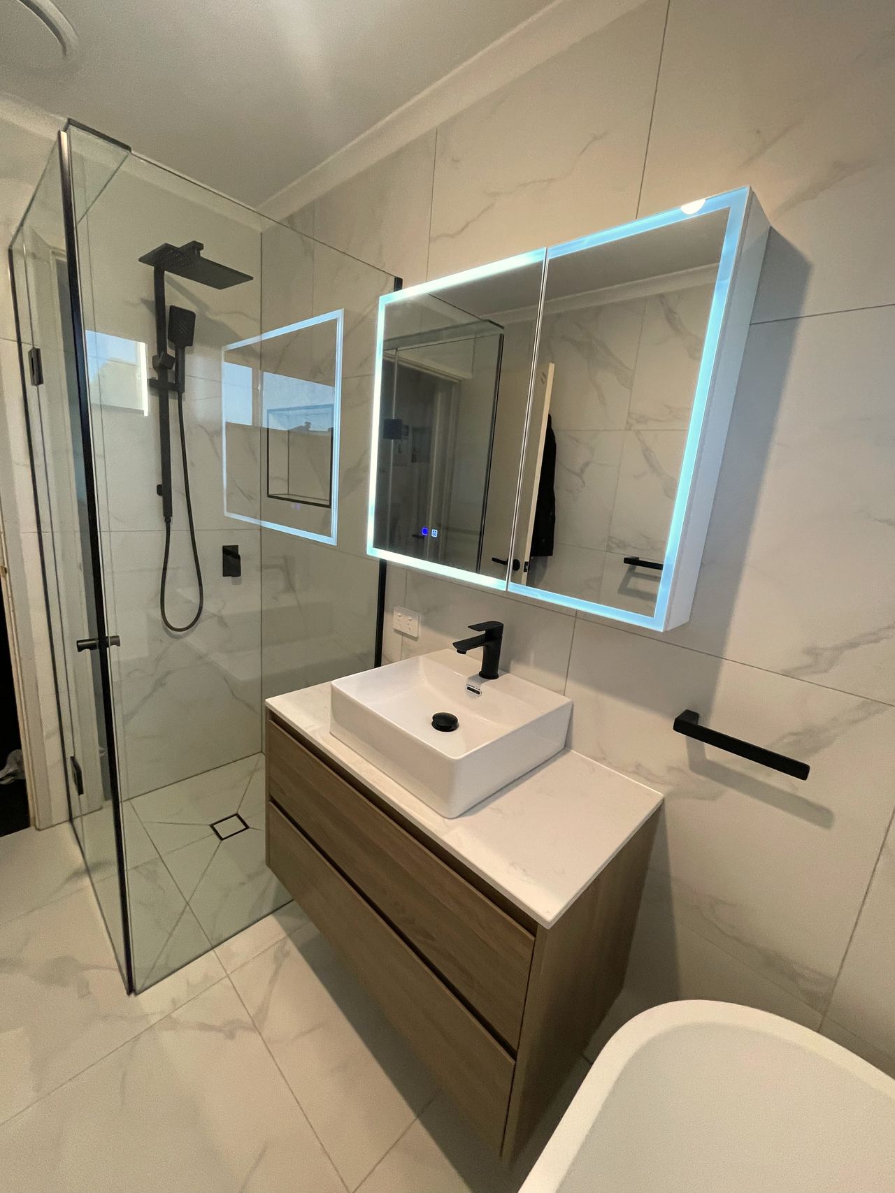 Wall-hung timber vanity with vessel basin and illuminated mirror cabinet in Cranbourne East