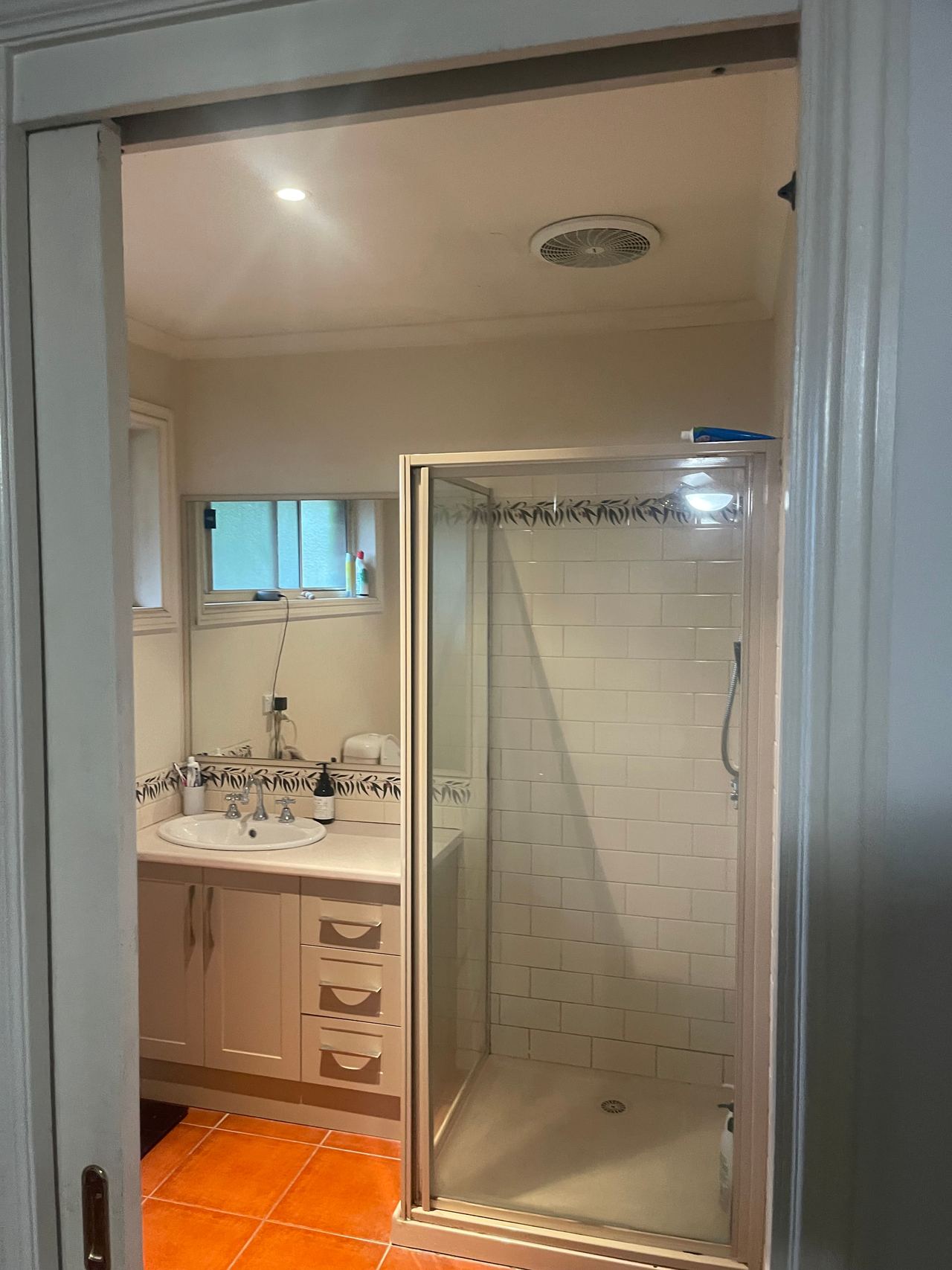 Before: dated Cranbourne North bathroom with terracotta floor tiles, framed shower and cream vanity