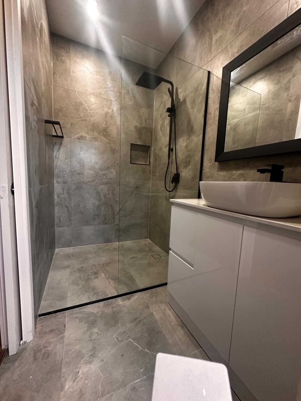 After: second Cranbourne West bathroom with a walk-in shower, black fittings and dark large-format tiles