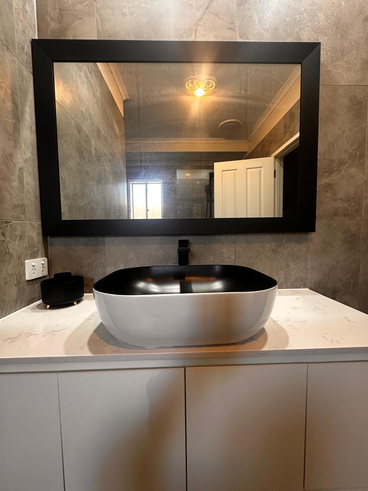 White vanity with stone-look vessel basin under a black-framed mirror in Cranbourne West