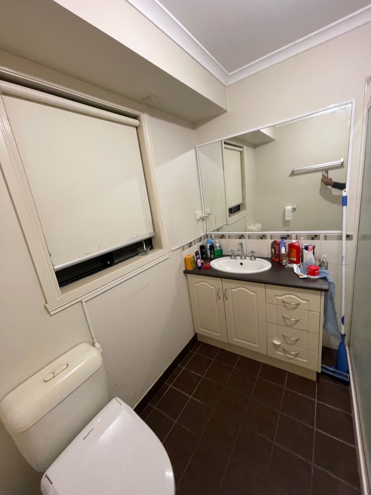 Before: dated bathroom with a cream vanity and dark floor tiles