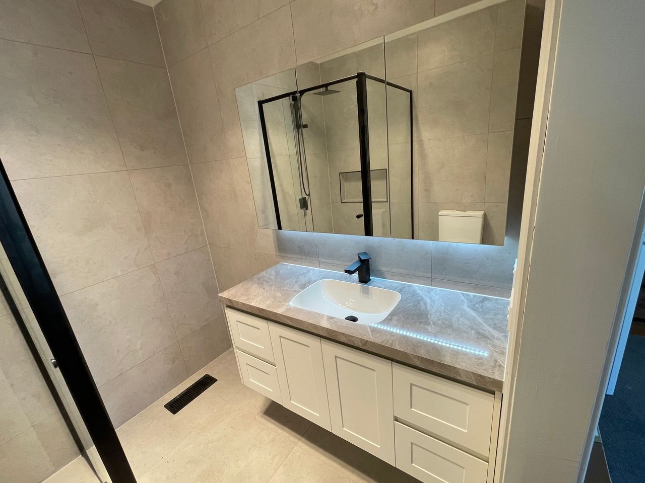 After: shaker vanity with a marble-look top and backlit mirror in Mitcham