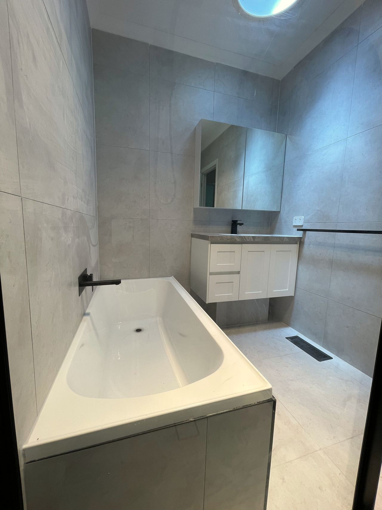 Tiled built-in bath with matte black wall spout in a renovated Mitcham bathroom