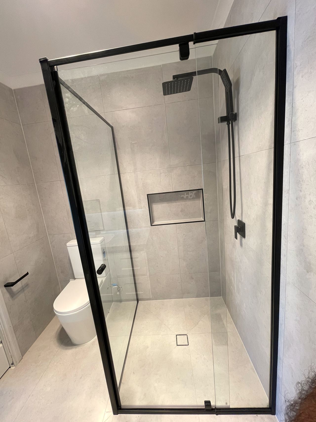 Renovated bathroom in Mitcham with a black-framed shower, recessed niche and full-height grey tiles