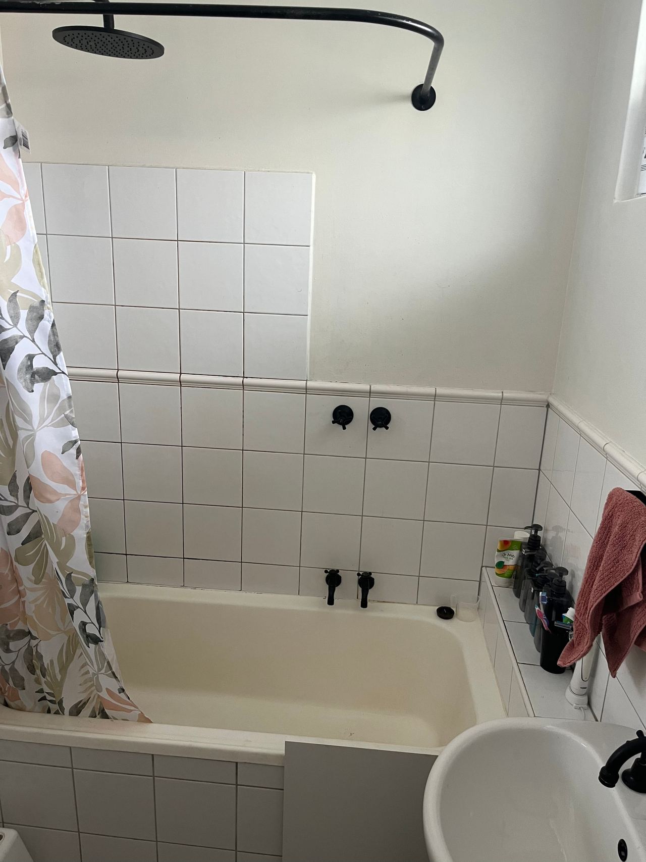 Before: original built-in bath with white wall tiles and a shower curtain