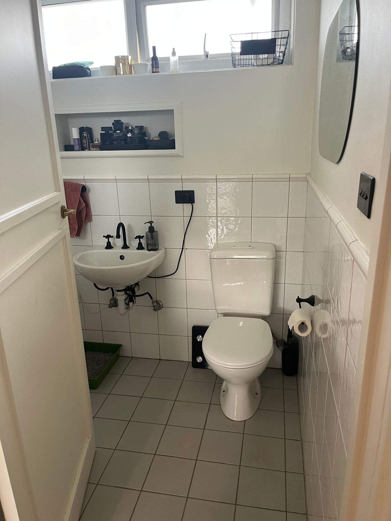 Before: original wall-hung basin and toilet with white wall and floor tiles