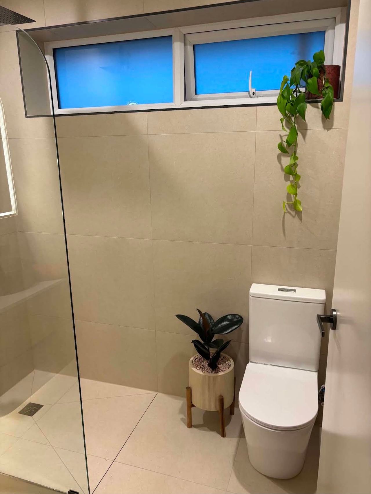 Walk-in shower with fixed glass panel and warm large-format tiles