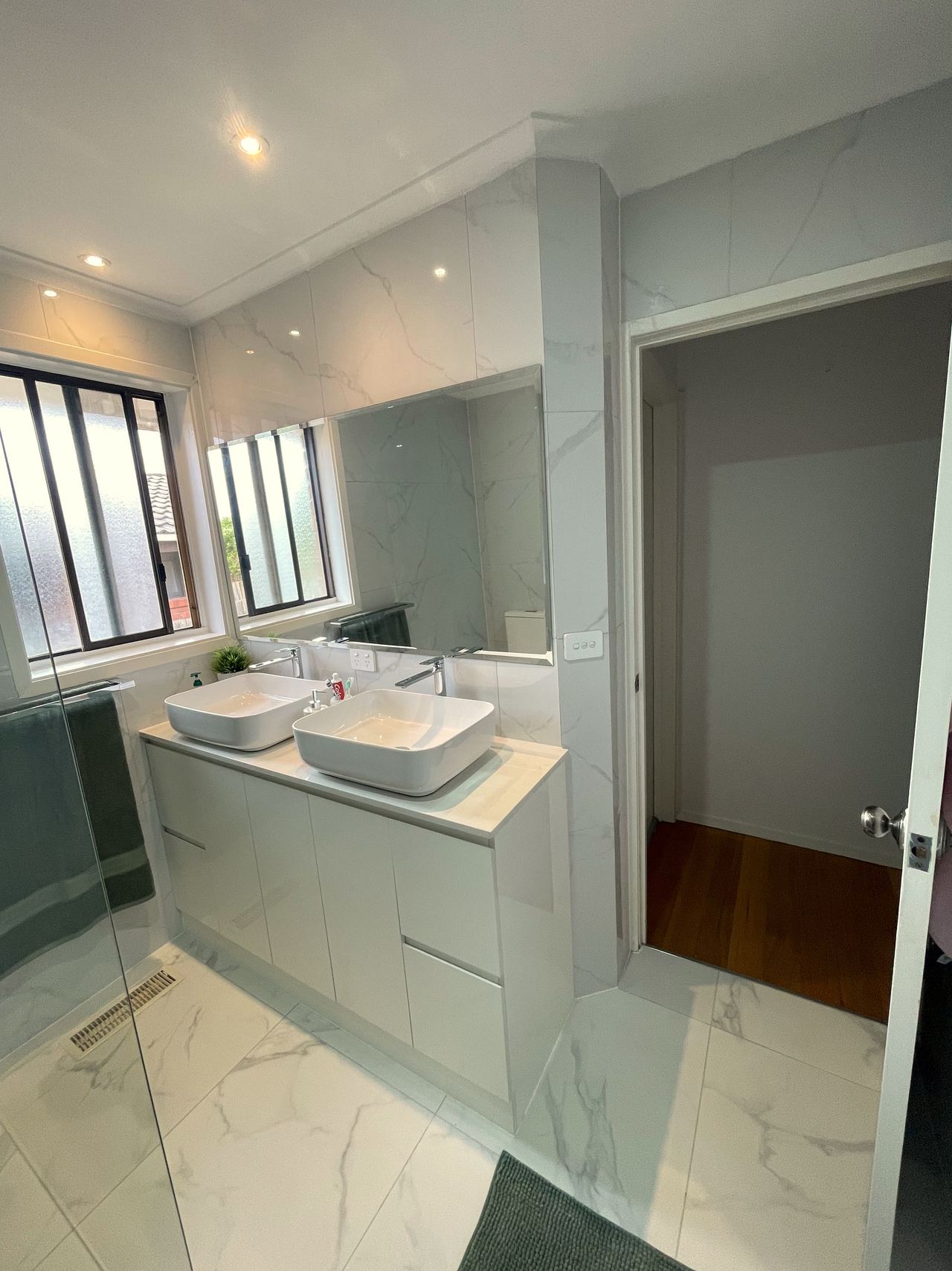 Renovated bathroom in Noble Park with a double vanity, twin vessel basins and marble-look tiles